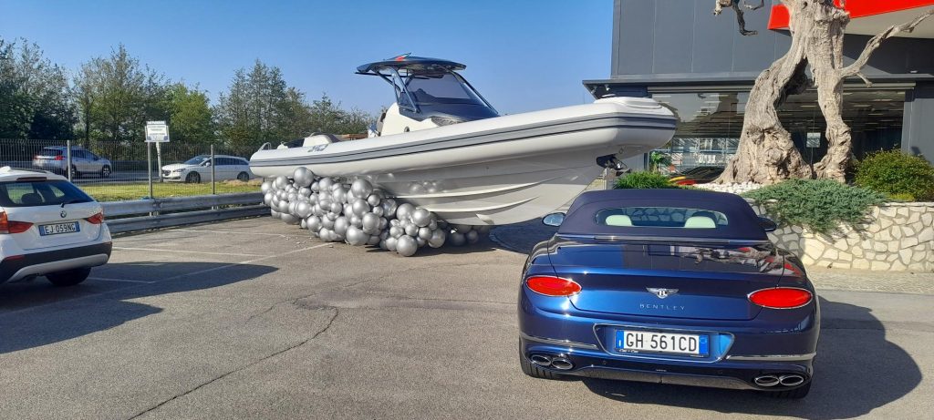 Gommone esposto su un'onda di palloncini argentati davanti a uno showroom