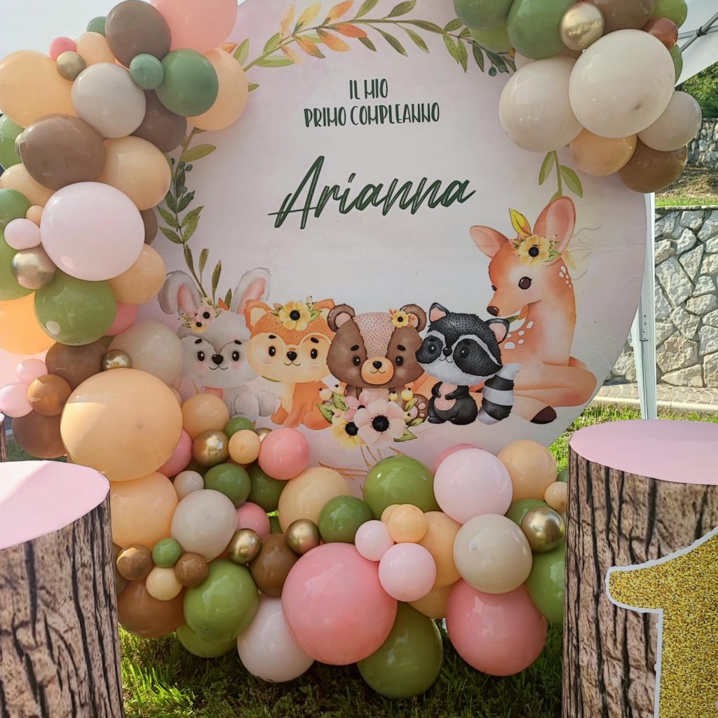 Allestimento a tema animali del bosco con palloncini verde salvia, pesca e rosa per un primo compleanno