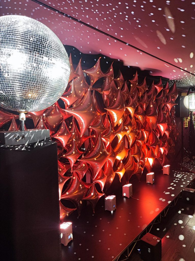 Parete e soffitto di palloncini a stella color rame dietro la pista da ballo per una festa dei 40 anni