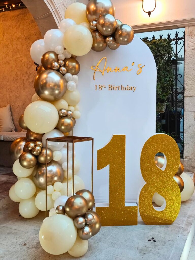 Ghirlanda di palloncini avorio e oro con pannello bianco e numeri 18 dorati per un diciottesimo